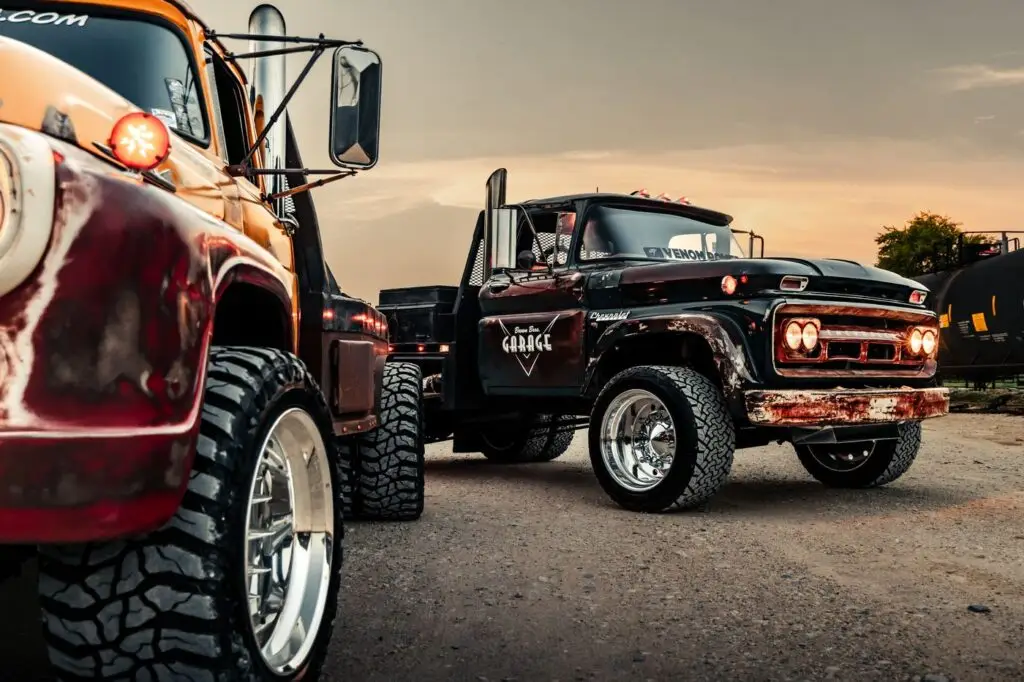Orange truck fender and polished wheel in the foreground with a black diesel truck behind