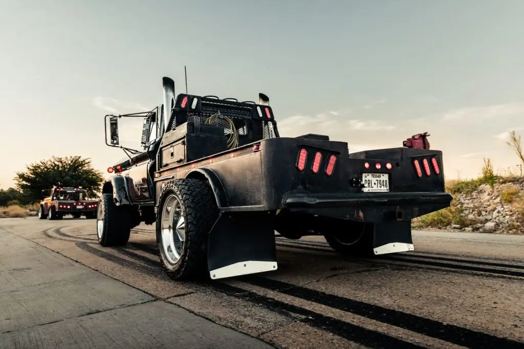 Rear view of a black flatbed diesel truck with red tail lights