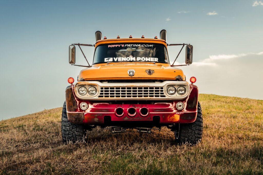 Front view of a vintage orange Ford diesel truck on a grassy hill