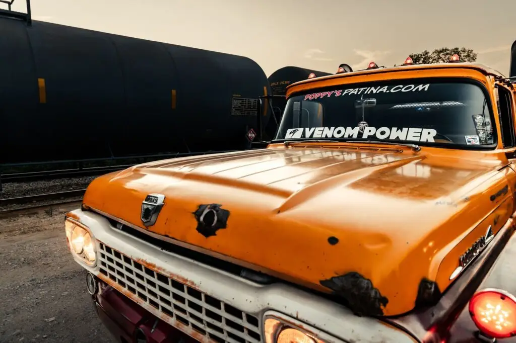 Front end of a vintage orange Ford diesel truck with custom headlights
