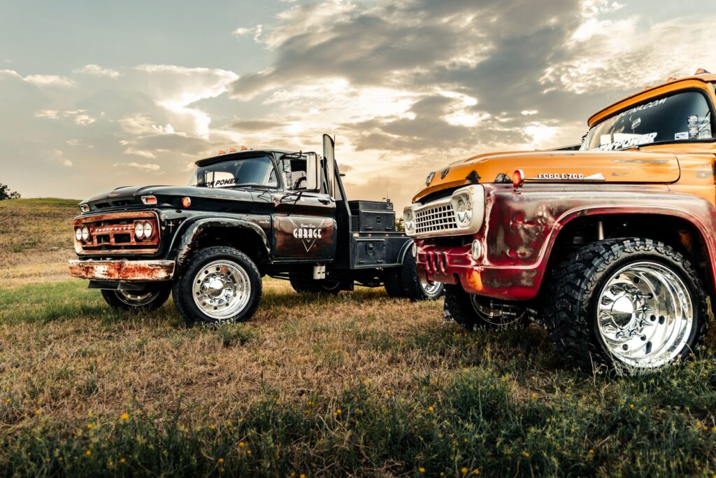 Black and orange custom diesel trucks side by side on a grassy hill